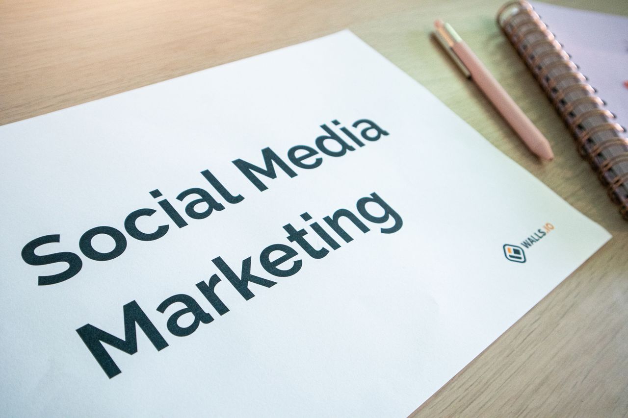 heros-img Gros plan sur un document de marketing sur les réseaux sociaux posé sur un bureau, avec un stylo et un carnet.